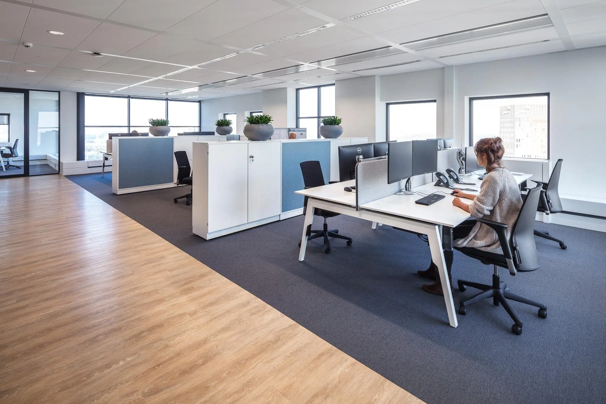 Moderne kantoorruimte in Rivium Quadrant met werkplekken, computers en een medewerker aan het bureau.